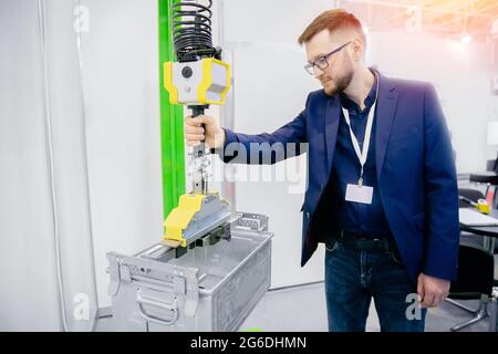 Worker engineer uses intelligent industrial manipulator lift easy with gripper in factory. Stock Photo