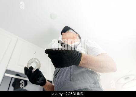 Electrician worker install replaces LED lighting lamp in apartment. Stock Photo