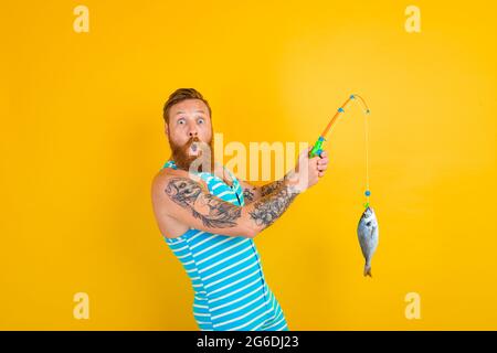 man with beard and swimsuit caught a fish Stock Photo