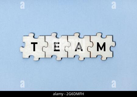 Team word on wooden puzzle pieces isolated on blue background. Top view Stock Photo