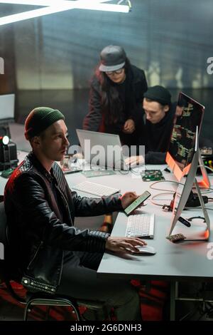 One of three swindlers using computer and smartphone while committing crime Stock Photo