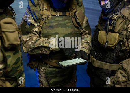 Three officers in camouflage outfit discussing location scheme in tablet Stock Photo