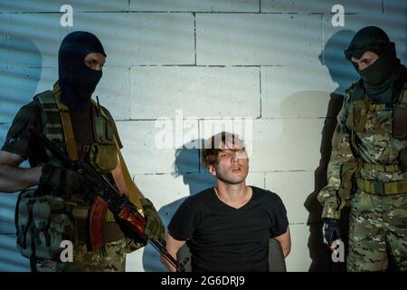 Two soldiers in military outfit standing by cyber criminal Stock Photo
