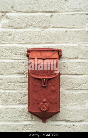 heavily painted red standard no 2 mailbox on a white brick background Stock Photo