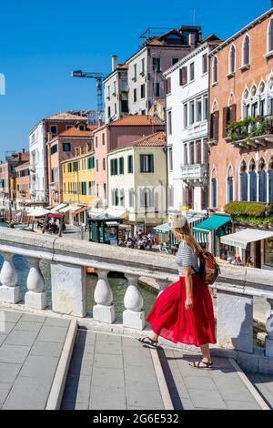 Young woman in red dress walking over Scalzi Bridge on the Grand Canal, Venice, Veneto, Italy Stock Photo