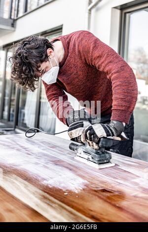 Young man doing DIY, grinding table with a grinder Stock Photo