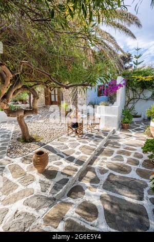 Courtyard, Greek home, Young woman having breakfast on holiday outside, Greece Stock Photo