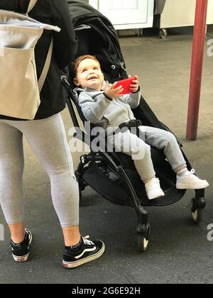 Toddler in stroller with cell phone Stock Photo