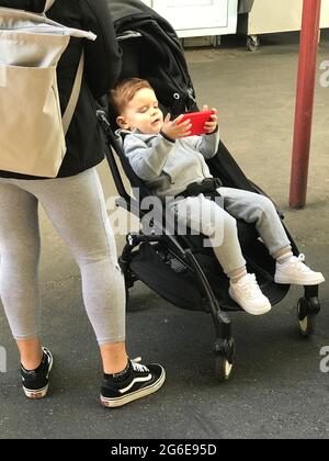 Toddler in stroller with cell phone Stock Photo