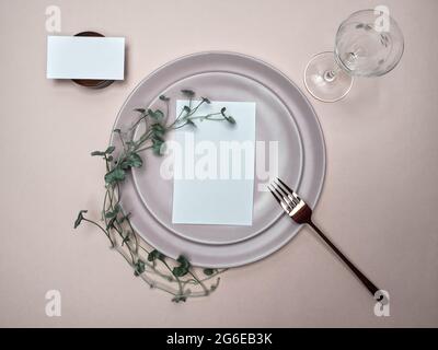 Table place and menu mockup. Wedding and Birthday table setting with foliage decoration. Overhead shot. Stock Photo