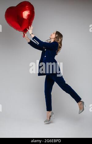 Woman in velvet suit with heart air balloon. Stock Photo