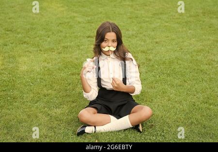 Funny party concept. Cute mustache. Small girl hold fake mustache on face. Happy childhood. Little child school uniform. Back to school. Small Stock Photo