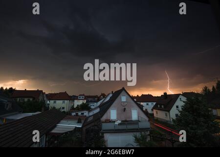 Thunderstrom and lightning with dark dramatic clouds and lighs of a car. Above a small city in Germany. Trossingen. Stock Photo