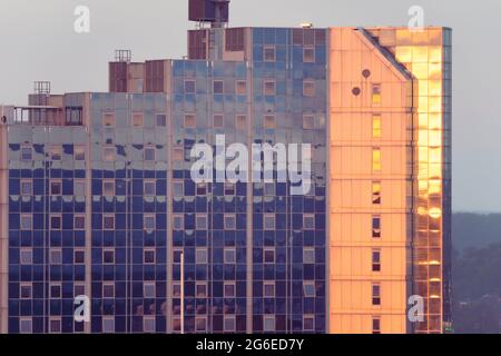 The setting sun turns the windows of Churchill Place, a high rise apartment building, deep orange in late June. Basingstoke, UK Stock Photo