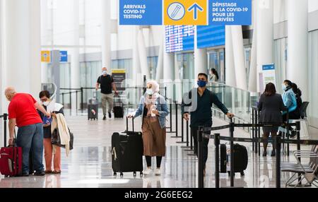 Mississauga, Canada. 5th July, 2021. Travelers wearing face masks walk out of the arrivals hall at Toronto Pearson International Airport in Mississauga, Ontario, Canada, on July 5, 2021. Starting from Monday, 'fully vaccinated' Canadians and permanent residents can enter Canada without undergoing quarantine. Credit: Zou Zheng/Xinhua/Alamy Live News Stock Photo