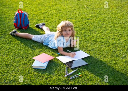 Cute lovely child reading book outside. Kid read book in park. Preparation for school and international literacy day. Back to school concept. Stock Photo