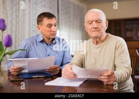 Adult man with elderly father analyzing papers Stock Photo