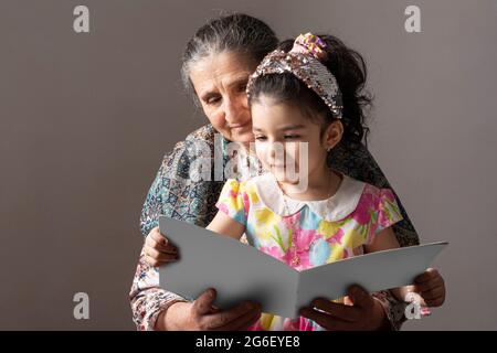 Senior grandmother with her granddaughter reading a book together, editable mock-up series template ready for your design, book cover selection path i Stock Photo