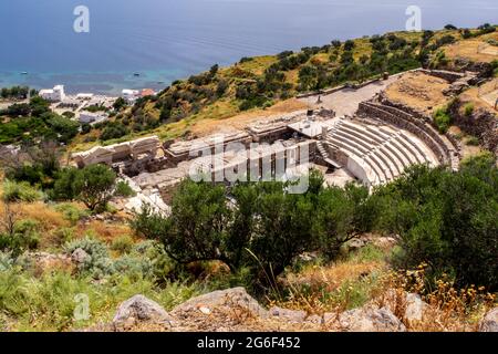 Ruins of Ancient Theater of Milos on a green hill with Mediterranean Sea in the background near Trypiti Town on Milos Island, Greece. Stock Photo