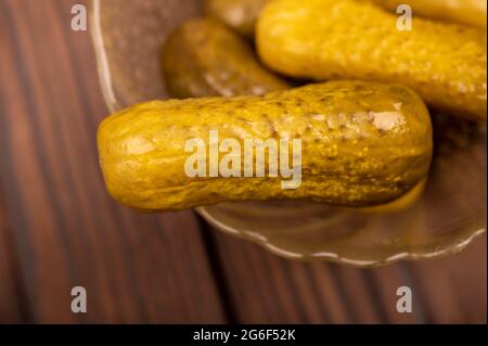 Pickled cucumbers in a glass dish on a wooden table. Close-up Selective focus Stock Photo