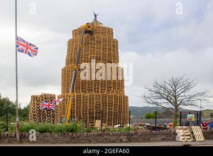 4 July 2021 Youths on top of the very tall bonfire made from thousands of wooden industrial pallets as they prepare for the 12th of July celebrations Stock Photo