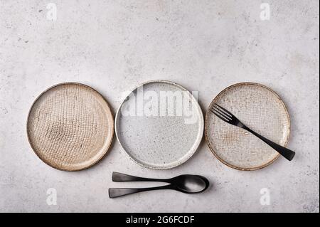 Empty light plates with fork and spoon set on gray wooden background. Top view, copy space Stock Photo