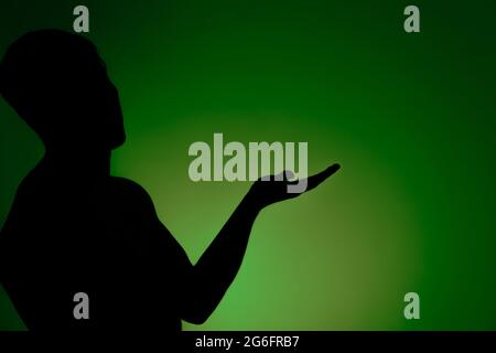 Studio photo of the silhouette of a young man with a hand raised Stock Photo