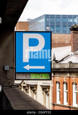 Multi storey car park P sign blue with bright green neon writing showing spaces and arrow. Carpark spaces available empty in England UK. Electric sign Stock Photo