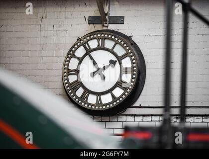 Old fashioned vintage big industry factory clock hanging with roman numerals in abandoned building no workers. Industrial workshop clocking off time Stock Photo