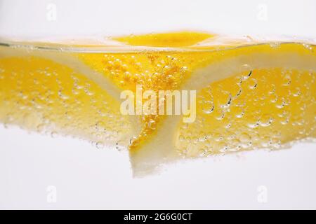 Extreme close up lemon wedge in sparkling water Stock Photo