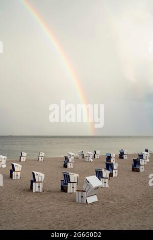 Rainbow over cabanas on tranquil ocean beach, Schleswig-Holstein, Germany Stock Photo