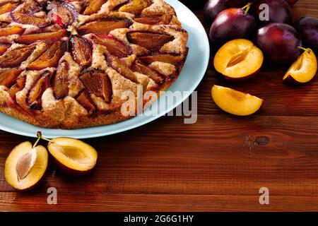 plum cake and plums, on wood background. Homemade baking. Stock Photo