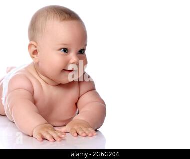 Portrait of happy infant child baby girl kid in diaper lying on her tummy, stomach looking aside at copy space Stock Photo