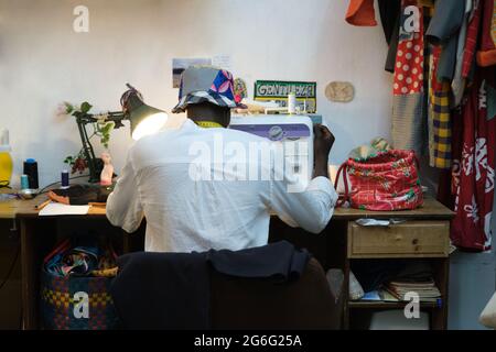 Black tailor working in a sewing shop making african clothes. Sewing workshop. Stock Photo