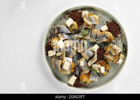 Salted herring beautifully chopped and decorated with onions and potatoes on a plate top view, pickled herring appetizer with a side dish, copy space. Stock Photo