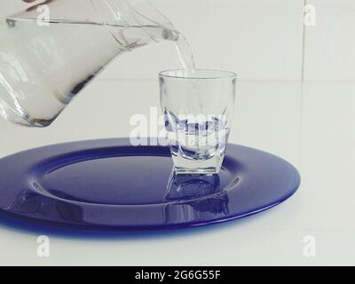 pouring water into a water glass with a carafe Stock Photo