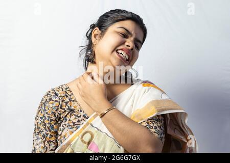 Isolated on white background an Indian woman in saree itching her neck for rashes Stock Photo