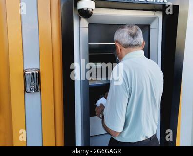 Retired man withdrawing money from ATM. Withdraw money. Withdraw money from the bank. Stock Photo