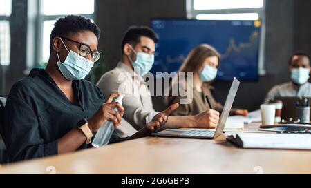Multicultural workers wearing medical masks, black woman using ...