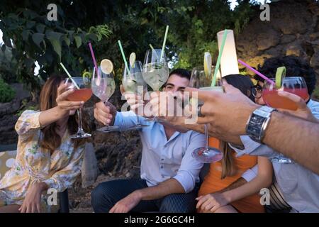 Group of young people who gather on the terrace garden for a cocktail party raising their glasses for a celebratory toast. Stock Photo