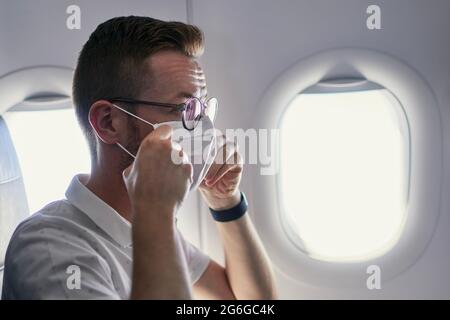 Passenger wearing protective face mask in airplane. Themes traveling in new normal and personal protection during pandemic covid-19. Stock Photo