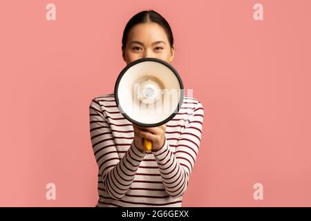 Portrait Of Young Asian Woman With Megaphone In Hands Making Announcement Stock Photo