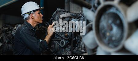 Attractive man working hard and fix Auto mechanic on car engine in mechanics garage. Repair service Stock Photo