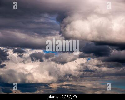 Dramatic heavy and dark rain clouds partially torn by the wind Stock Photo