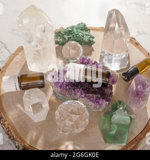 Essential oil glass bottles, beautiful crystals and gemstones on wooden log slice. Healing minerals and essential oil bottles for alternative medicine Stock Photo