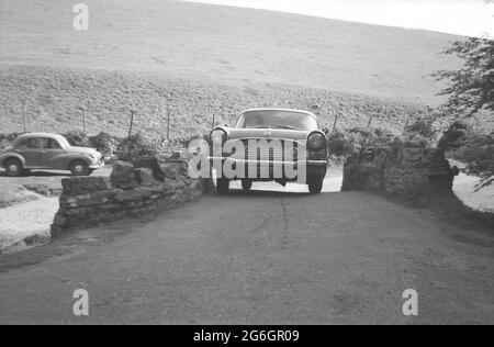 1960s, historical, mind the gap....a car of the era, possibly a Vuaxhall Cresta, on a rural road going over a small, narrow, stone built humped bridge, England, UK. Stock Photo