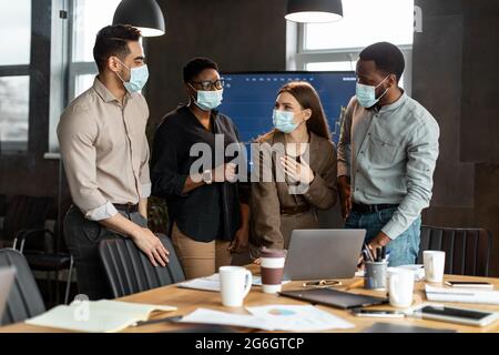 Colleagues in masks having meeting in boardroom, talking Stock Photo