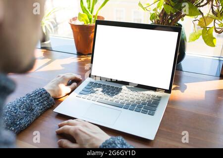 Mockup image, laptop computer with white blank screen close up and back view of businessman in casual clothes. Stock Photo