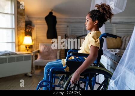 Black little girl with disability in wheelchair at home Stock Photo
