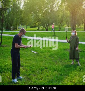 Married couple in face masks playing in nature, family sports park lawn Stock Photo